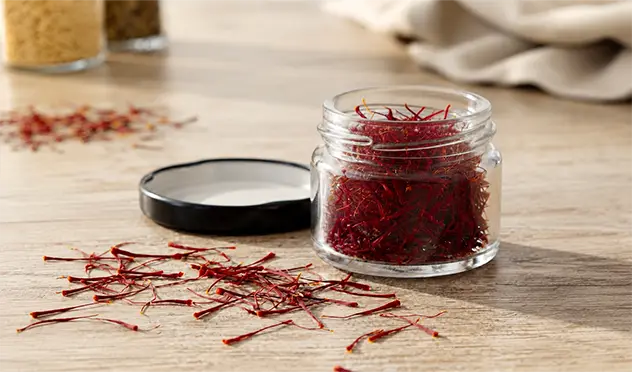 Premium Mongra saffron threads in a glass jar on a wooden table